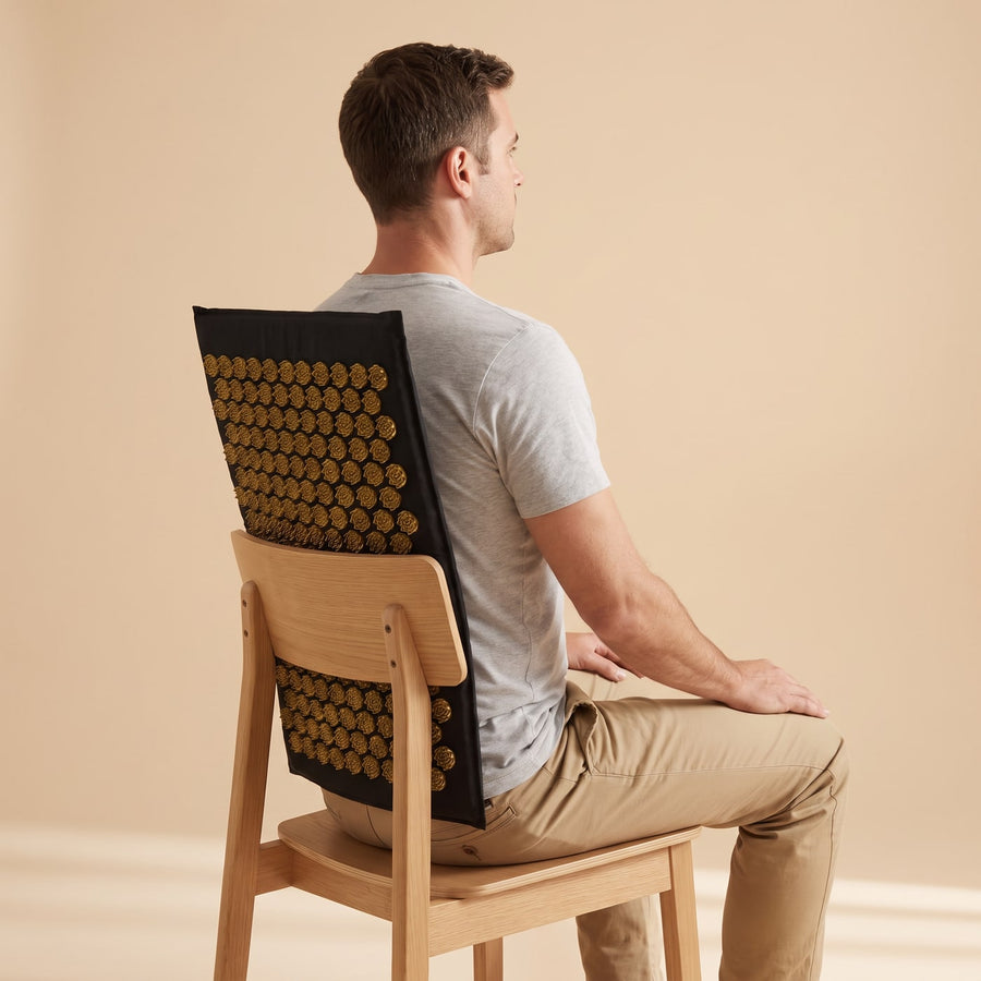 Position assise : le tapis d'acupression PuraDorse calé entre le dossier de la chaise et les omoplates